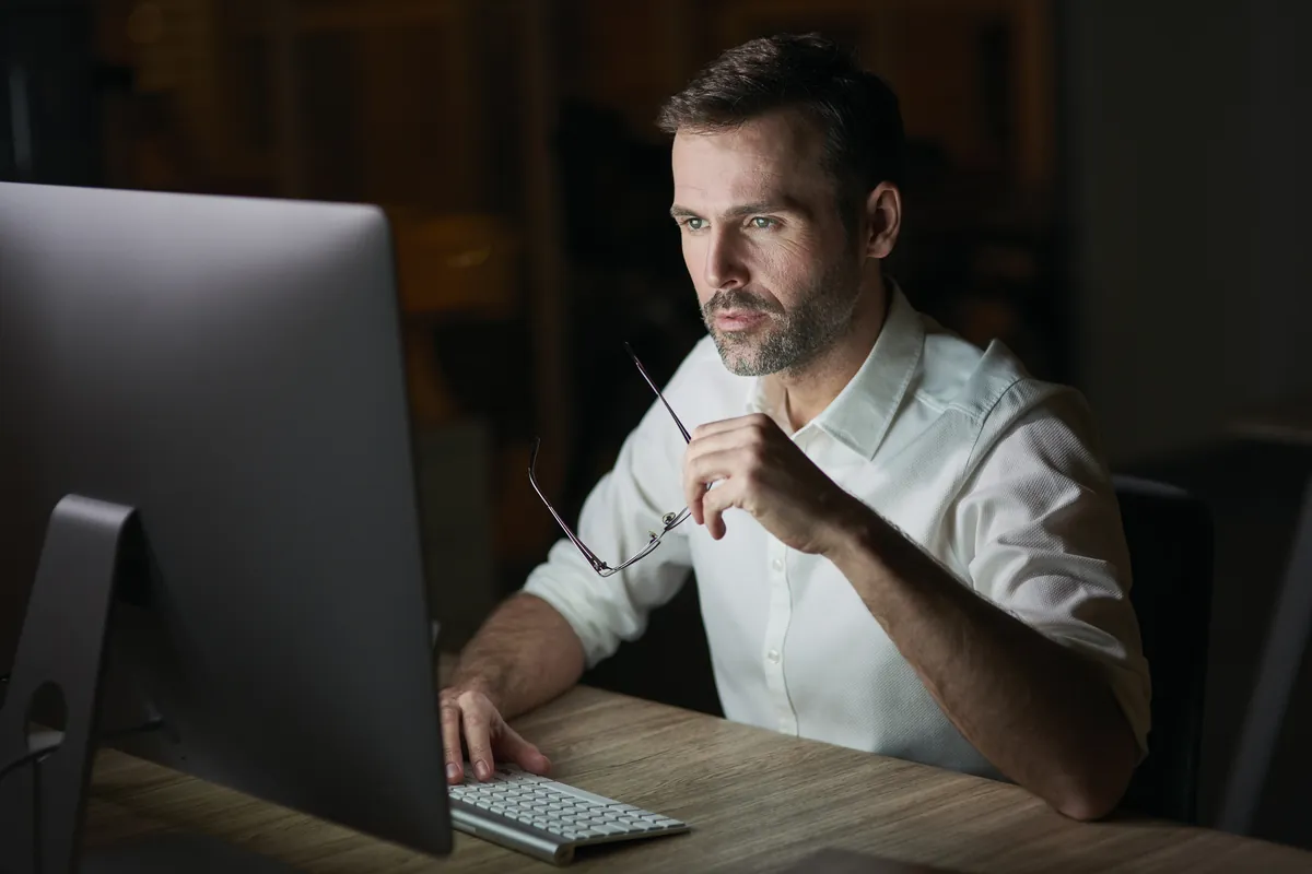 Empresario analizando números en la pantalla de la computadora por la noche